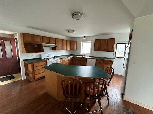 kitchen with a kitchen island, sink, white appliances, and dark wood-type flooring