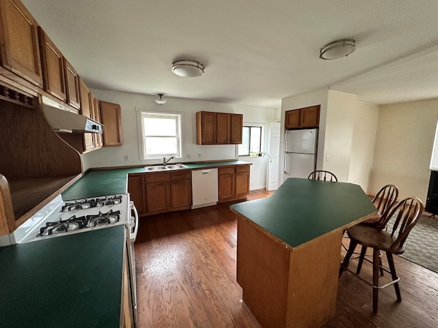 kitchen featuring a center island, white appliances, a kitchen breakfast bar, sink, and dark hardwood / wood-style flooring