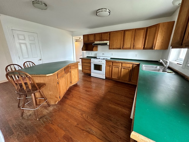 kitchen with white gas range, a breakfast bar, sink, a center island, and dark hardwood / wood-style floors