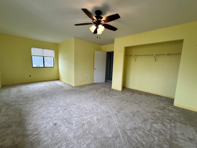 unfurnished bedroom featuring dark colored carpet, a closet, and ceiling fan