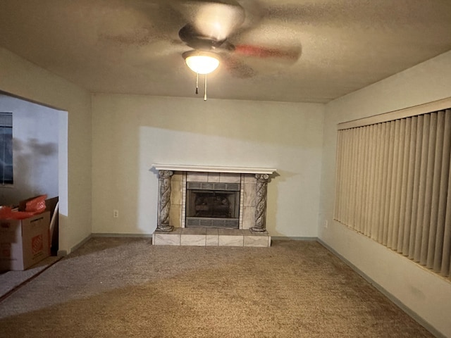 unfurnished living room featuring a tile fireplace, ceiling fan, carpet floors, and a textured ceiling