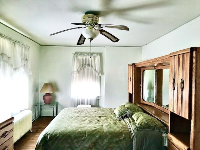 bedroom with radiator, ceiling fan, and dark hardwood / wood-style flooring