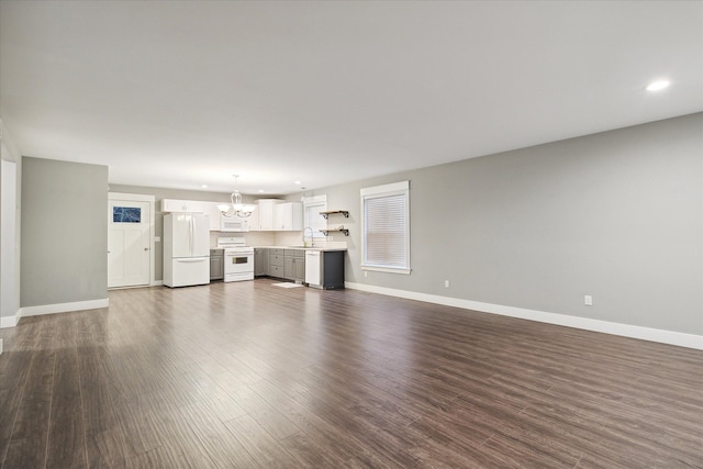 unfurnished living room with dark hardwood / wood-style floors, an inviting chandelier, and sink