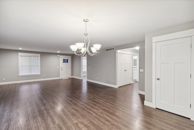 spare room featuring dark hardwood / wood-style flooring and a notable chandelier