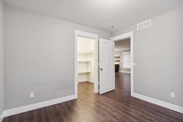 unfurnished bedroom with dark hardwood / wood-style floors, a spacious closet, and a closet