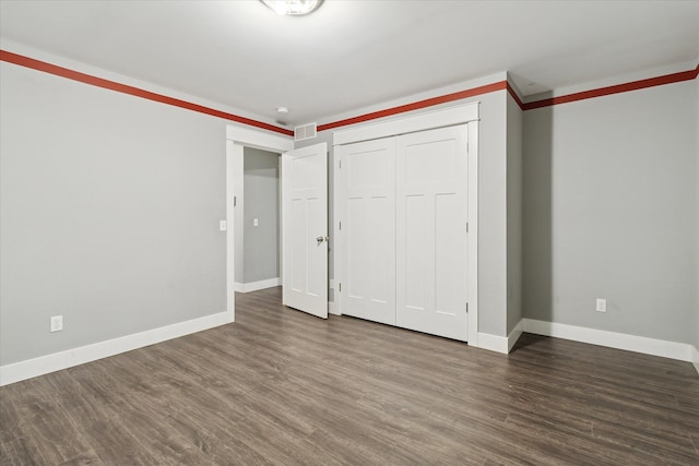 unfurnished bedroom with dark hardwood / wood-style flooring, ornamental molding, and a closet