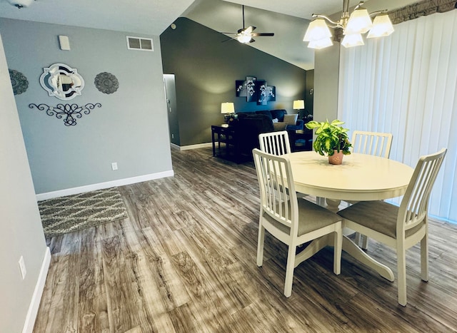 dining area featuring ceiling fan with notable chandelier, wood-type flooring, and vaulted ceiling