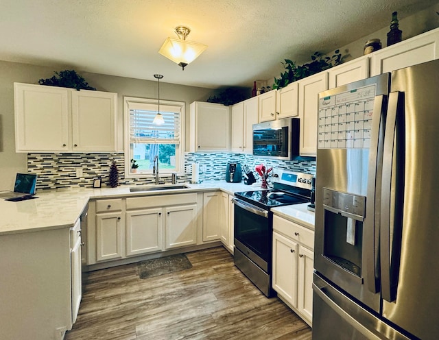 kitchen featuring hanging light fixtures, sink, white cabinets, and stainless steel appliances