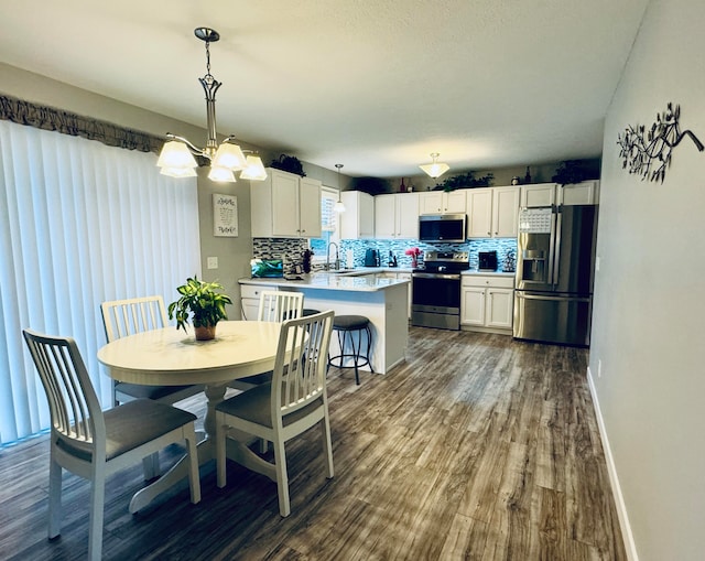 dining space with dark hardwood / wood-style floors, sink, and an inviting chandelier