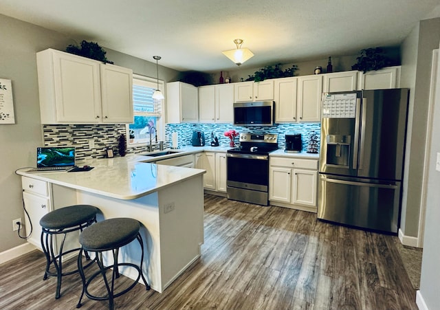 kitchen with white cabinets, sink, dark hardwood / wood-style floors, decorative light fixtures, and stainless steel appliances