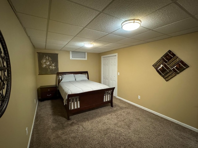 carpeted bedroom featuring a paneled ceiling and a closet