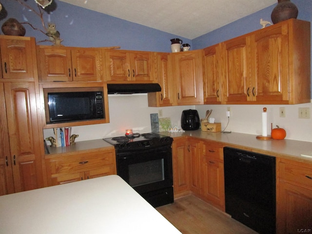 kitchen featuring black appliances, light hardwood / wood-style floors, and lofted ceiling