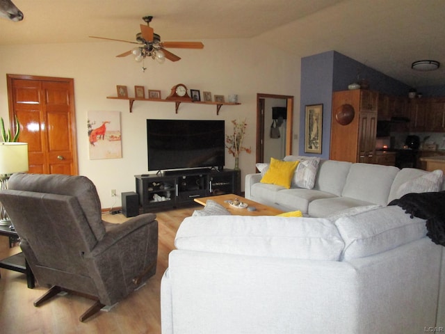 living room featuring ceiling fan, light hardwood / wood-style floors, and vaulted ceiling