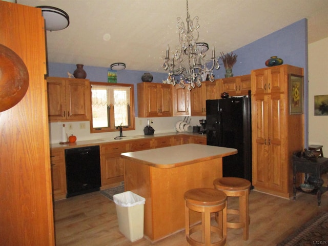 kitchen featuring a center island, an inviting chandelier, black appliances, a kitchen breakfast bar, and light hardwood / wood-style floors