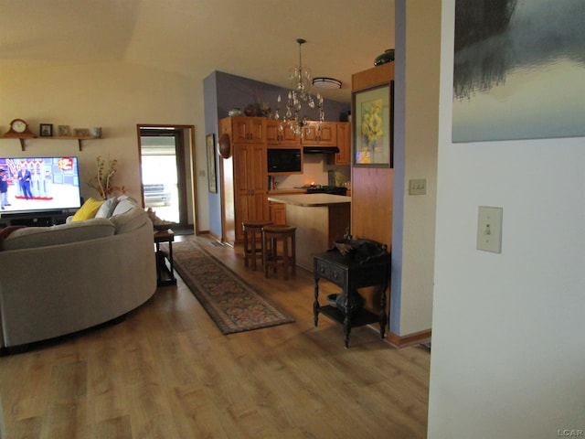 living room featuring hardwood / wood-style floors, an inviting chandelier, and vaulted ceiling