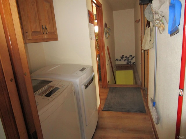 laundry area featuring cabinets, hardwood / wood-style floors, and washing machine and clothes dryer