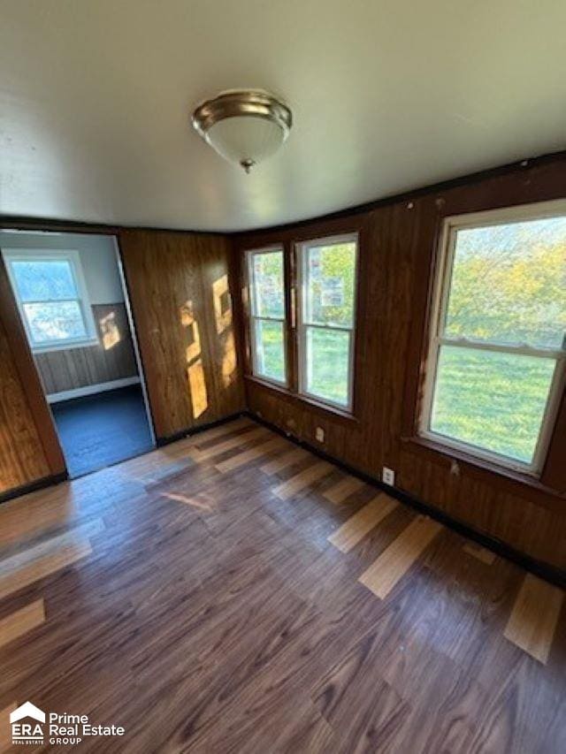 unfurnished living room with wood walls and dark wood-type flooring