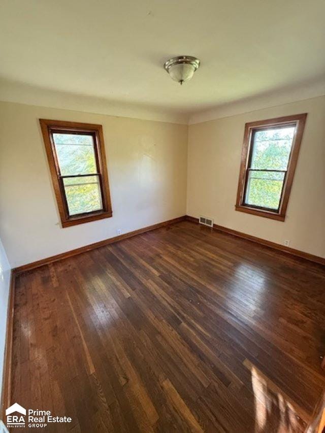 empty room with dark wood-type flooring and a healthy amount of sunlight