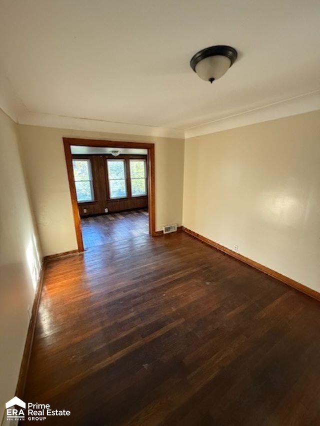 spare room with dark hardwood / wood-style flooring and crown molding