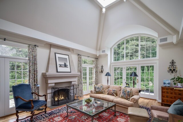 living room with hardwood / wood-style floors, high vaulted ceiling, and french doors