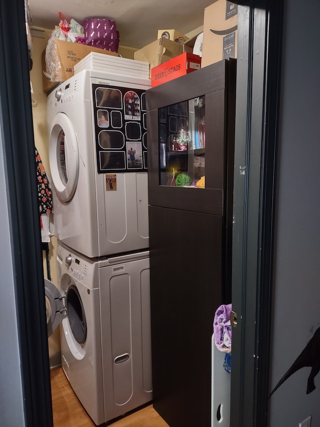 laundry area featuring hardwood / wood-style floors and stacked washing maching and dryer