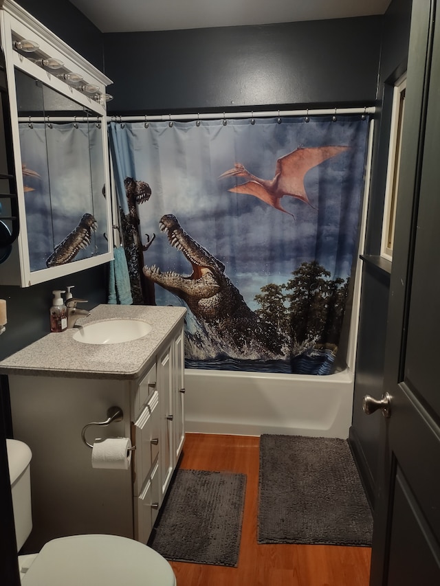 full bathroom featuring hardwood / wood-style floors, vanity, shower / tub combo, and toilet