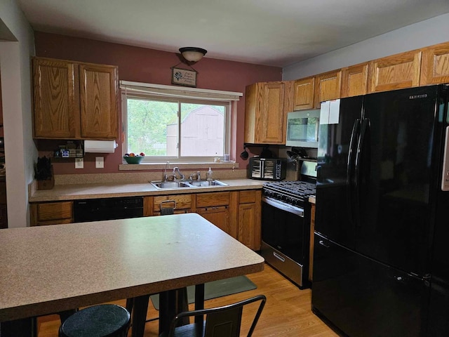 kitchen with sink, black appliances, and light wood-type flooring