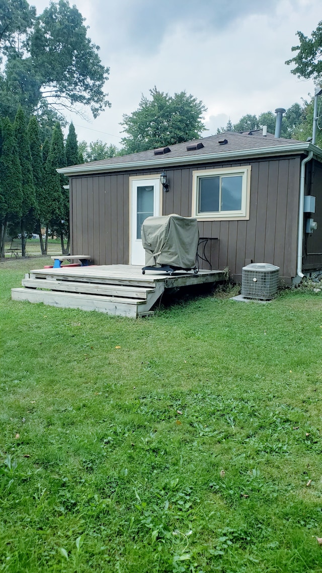 back of property featuring a deck, central AC unit, and a lawn