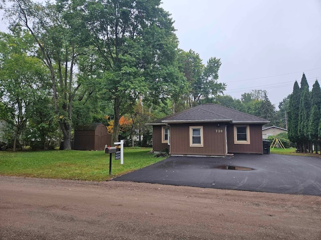 view of front of house with a front lawn and a storage unit