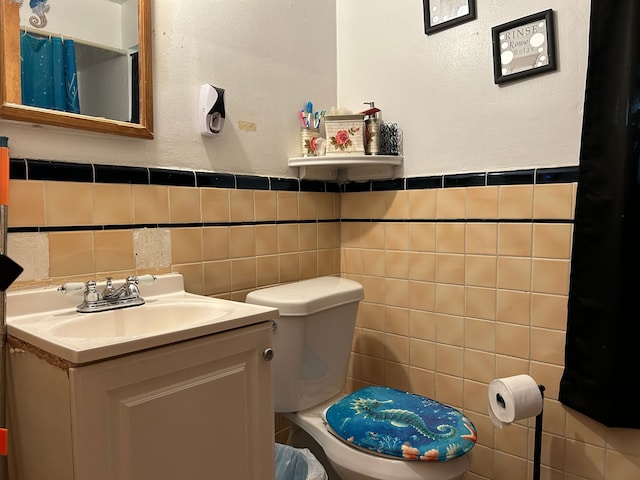 bathroom with vanity, toilet, and tile walls