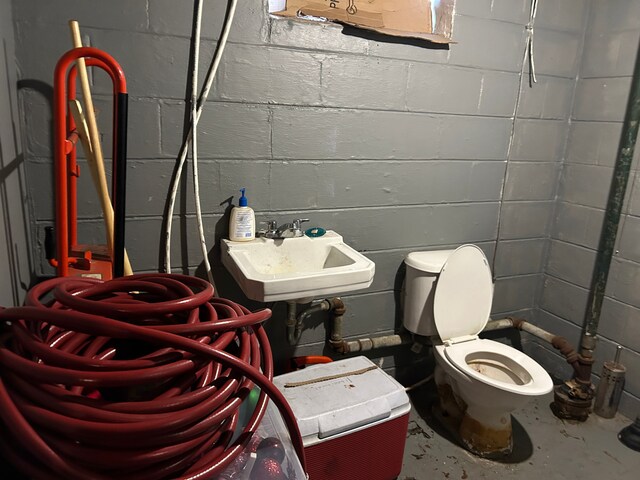 12644 Corbett St, Detroit, MI 48213 - half bath with a sink, toilet, concrete block wall, and unfinished concrete floors