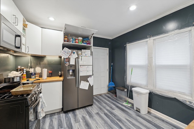 kitchen featuring crown molding, white cabinets, stainless steel appliances, and light wood-type flooring