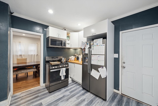 kitchen featuring wooden counters, crown molding, light hardwood / wood-style flooring, appliances with stainless steel finishes, and white cabinetry