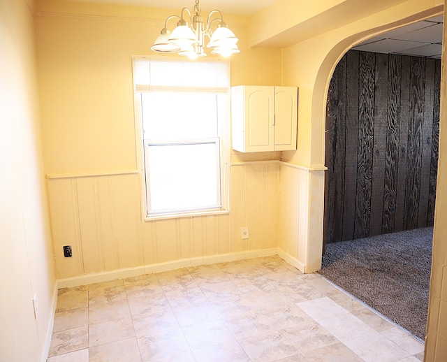 unfurnished room featuring plenty of natural light and a notable chandelier