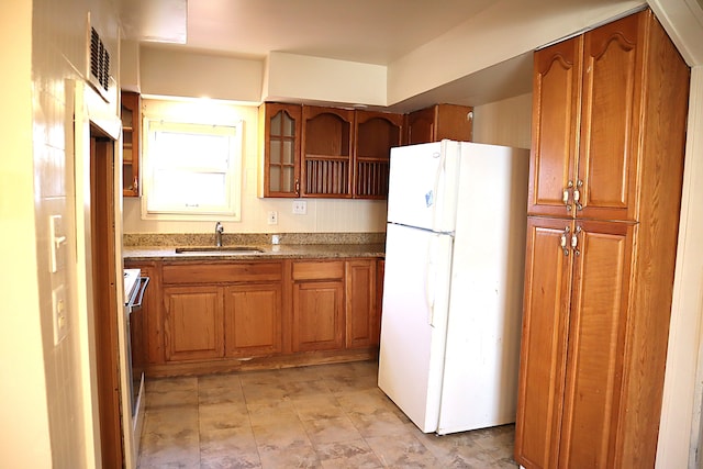 kitchen with light stone countertops, white appliances, and sink