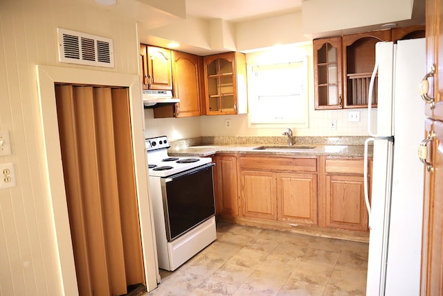 kitchen featuring light stone countertops, white appliances, and sink