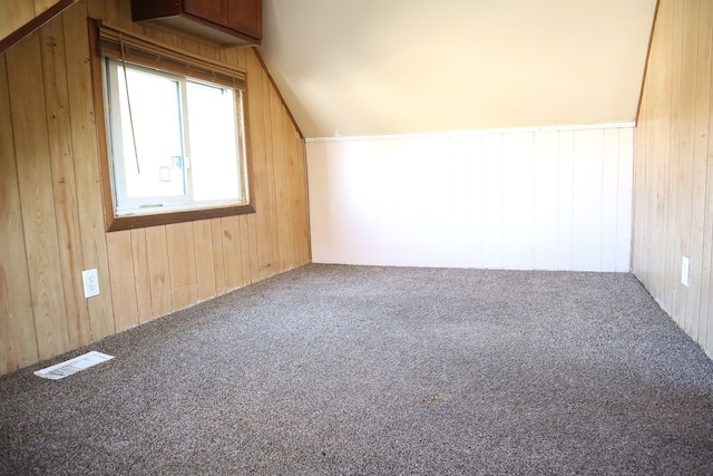 additional living space featuring carpet flooring, wood walls, and vaulted ceiling