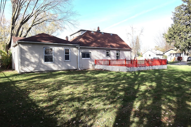 back of property with a deck and a lawn