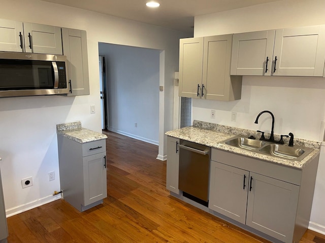 kitchen with dark hardwood / wood-style floors, gray cabinets, sink, and appliances with stainless steel finishes