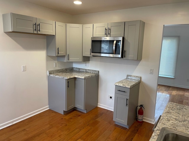 kitchen featuring gray cabinets, light stone countertops, and dark hardwood / wood-style floors