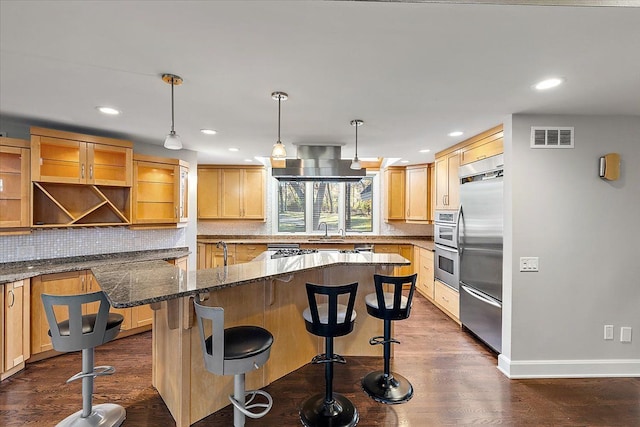 kitchen with dark hardwood / wood-style floors, a kitchen bar, dark stone countertops, and appliances with stainless steel finishes