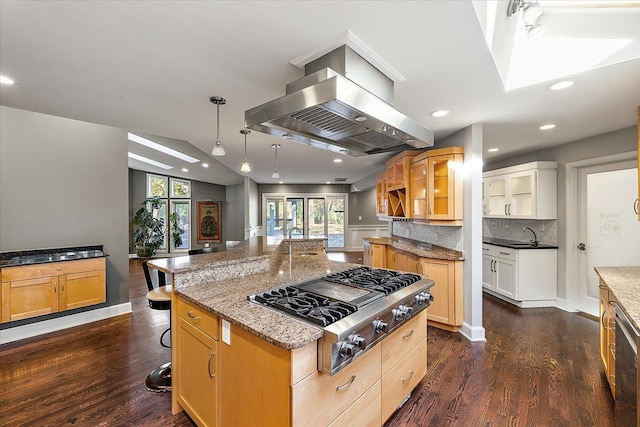 kitchen with dark hardwood / wood-style flooring, a large island with sink, stainless steel gas stovetop, a kitchen bar, and island range hood