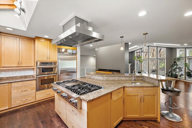 kitchen with light stone counters, a breakfast bar, island range hood, stainless steel appliances, and dark hardwood / wood-style floors