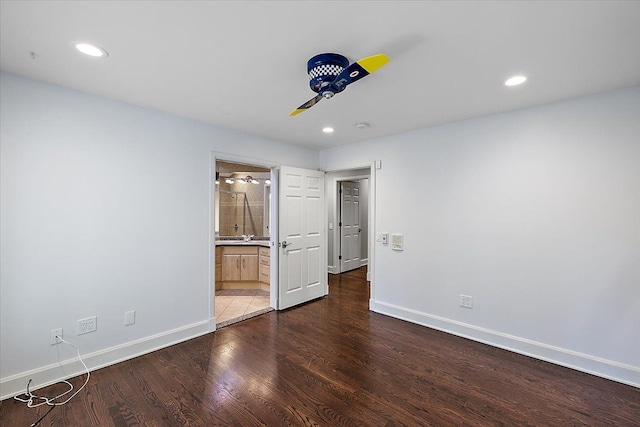 unfurnished bedroom with connected bathroom and dark wood-type flooring