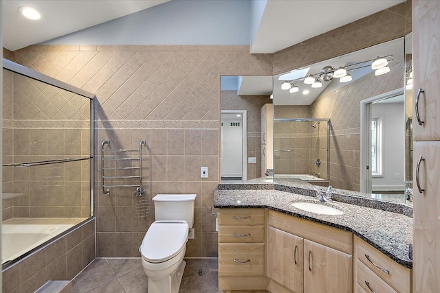 full bathroom featuring vanity, vaulted ceiling, tile walls, tile patterned flooring, and toilet