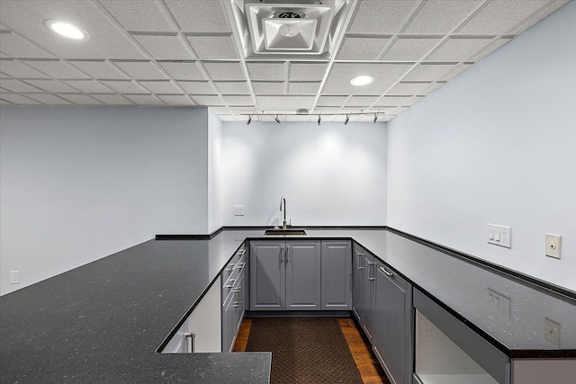 kitchen with a drop ceiling, rail lighting, sink, dark hardwood / wood-style floors, and gray cabinets