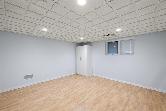 basement with a paneled ceiling and light wood-type flooring