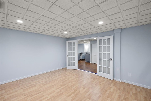 interior space featuring french doors, light hardwood / wood-style floors, and a drop ceiling