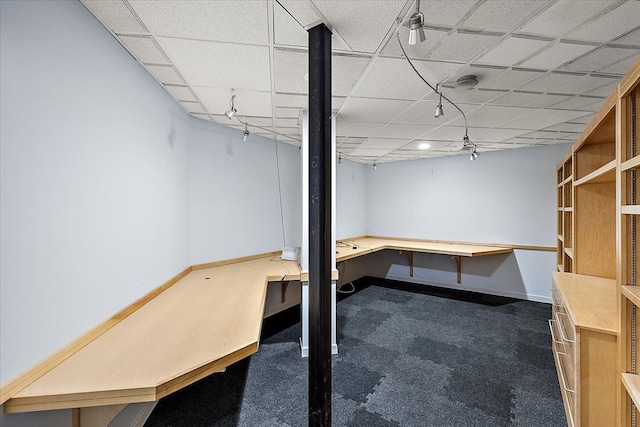 basement featuring a paneled ceiling and dark colored carpet