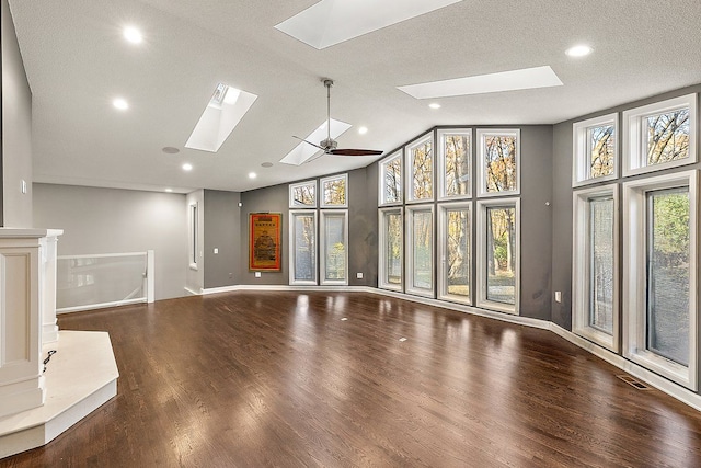 unfurnished living room with a skylight, ceiling fan, high vaulted ceiling, hardwood / wood-style floors, and a textured ceiling